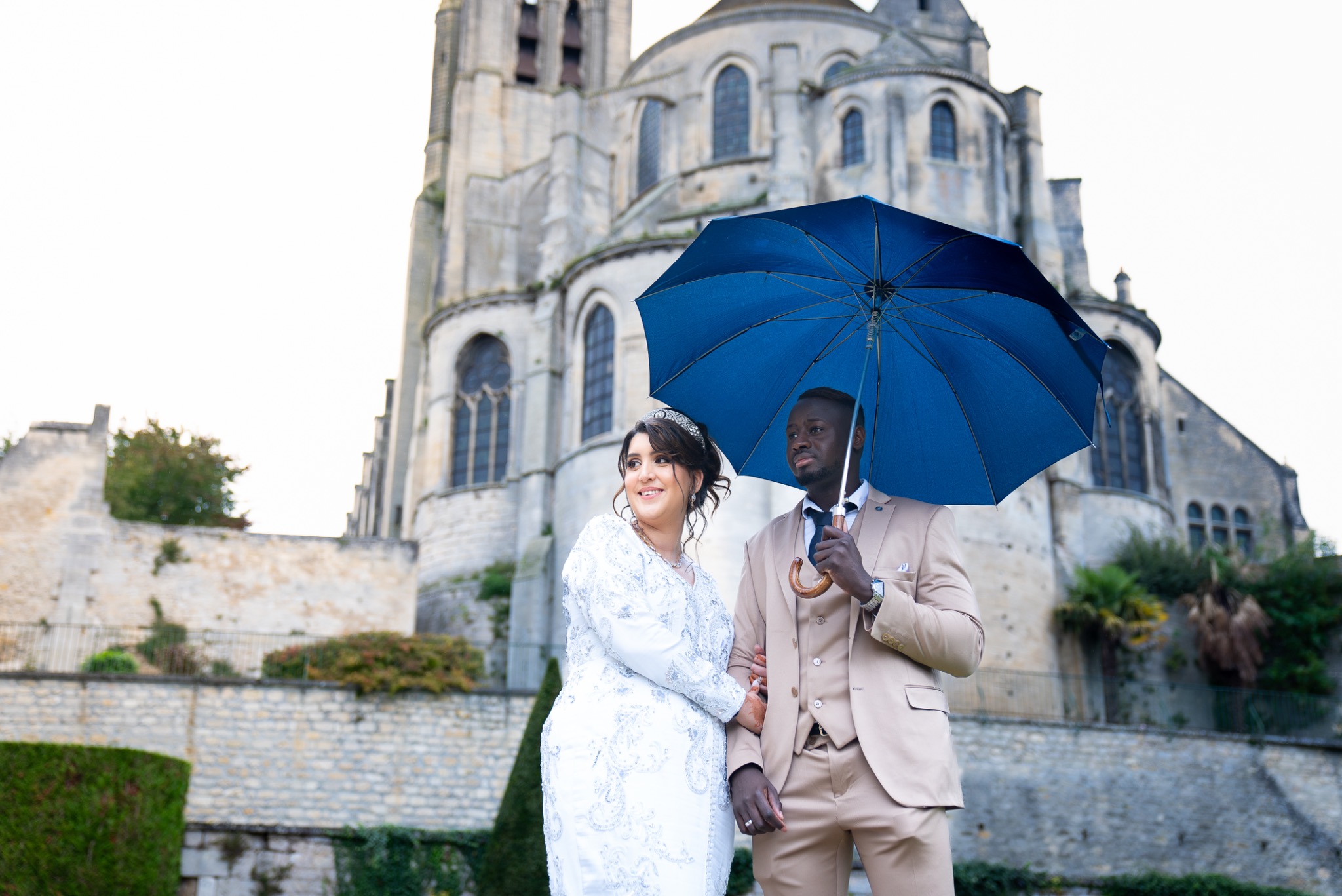 Un couple de mariés sous un parapluie bleu — photographie fournie par Ziris Studio